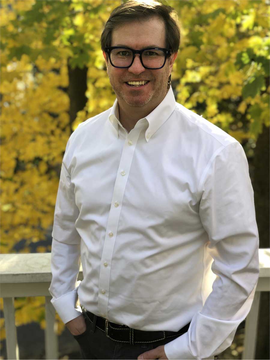 white man with glasses and button up shirt outdoors